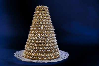A cone-shaped wedding cake made of stacked cookies and frosting.