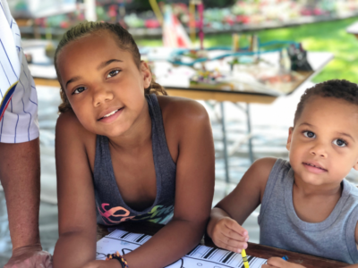 A boy and girl are doing a craft project outside.