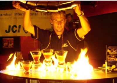 Bartender is mixing several drinks at once with tumblers over his head.