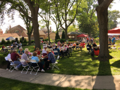 People sitting in chairs on a sunny lawn in outside.
