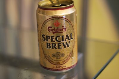 An open can of Carlsberg Special Brew beer sits on a glass surface