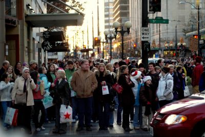 Crowds of people in a big city wait in lines with shopping bags on Black Friday.