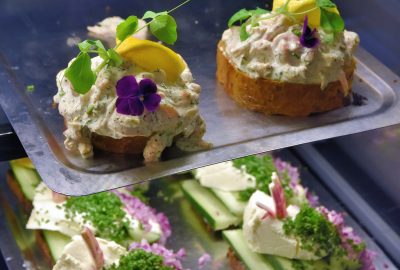 Open-faced sandwiches with many food toppings, flowers and herbs.