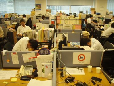 A office full of overworked employees sleep at their desks.