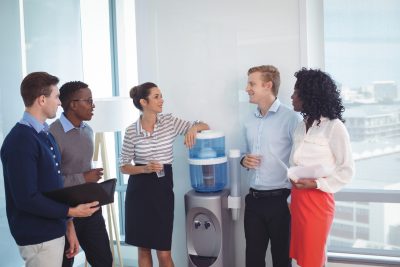 A group of young workers talk around a water cooler.